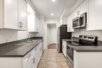A kitchen with white cabinets and black appliances.